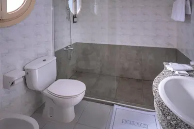 a white bathroom with a toilet and a sink at Hotel Sorrabona in Pineda de Mar