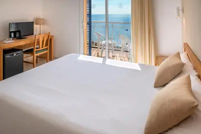 a bedroom with a large white bed with a desk and a window at Hotel Sorrabona in Pineda de Mar