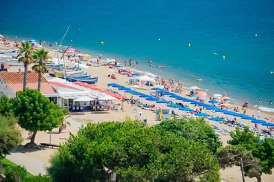 a beach with many people and umbrellas and the ocean at Hotel Sorrabona in Pineda de Mar