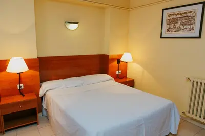 a bedroom with a white bed and two lamps at Aparthotel Bertrán in Barcelona