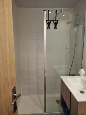 a shower with a glass door next to a sink at Candela's Beach Port in Masnou