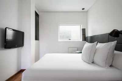 a white bedroom with a bed and a tv at Suites Avenue in Barcelona