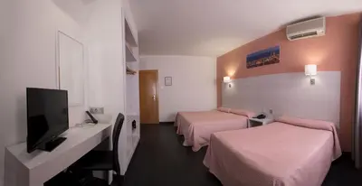 a hotel room with two beds and a flat screen tv at Cuatro Naciones in Barcelona