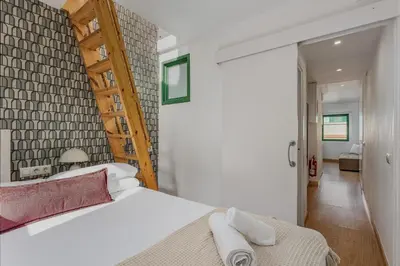 a bedroom with a white bed and a wooden ladder at Ola Living Vidreria in Barcelona