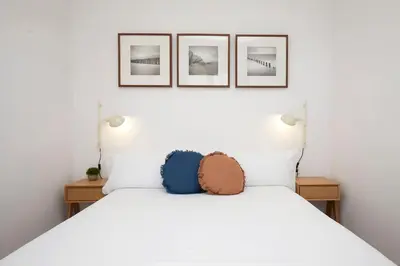 a bedroom with a white bed with three pictures on the wall at Fisa Rentals Aribau in Barcelona