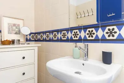 a bathroom with a white sink and blue and white tiles at Cal Mateu 11 huéspedes - Sagrada Família in Barcelona