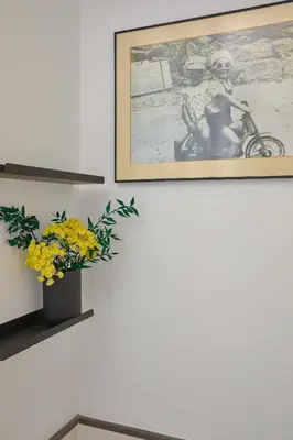a wall with a picture and a vase with yellow flowers at Cal Mateu 11 huéspedes - Sagrada Família in Barcelona
