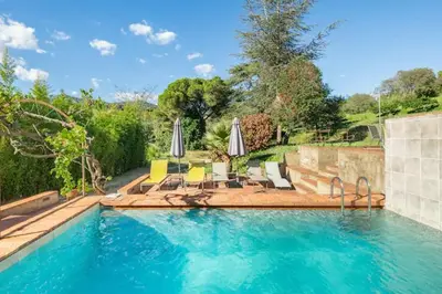 a large swimming pool with chairs and umbrellas at Can Rovira - Stunning Neoclassical Mansion, Just 20 min drive from Barcelona City Center, Ideal for groups and families in Alella
