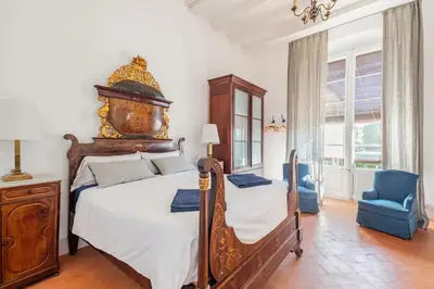 a bedroom with a large bed and a blue chair at Can Rovira - Stunning Neoclassical Mansion, Just 20 min drive from Barcelona City Center, Ideal for groups and families in Alella