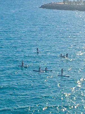 a group of people on surfboards in the water at The Magic Sea Front by Hello Homes Sitges in Sitges