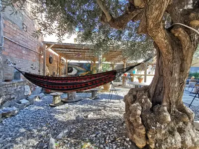 a hammock hanging from a tree next to a building at Mucha Masia Hostel Rural Urba in El Prat de Llobregat