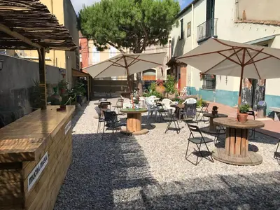 an outdoor patio with tables and chairs and umbrellas at Mucha Masia Hostel Rural Urba in El Prat de Llobregat