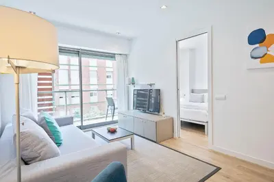 a living room with a white couch and a tv at Lugaris Rambla Apartments in Barcelona