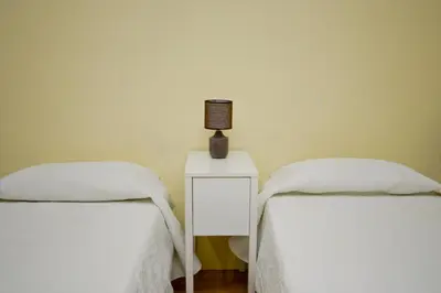 two beds with white sheets and a lamp on a table at Barcelona City Apartment in Barcelona