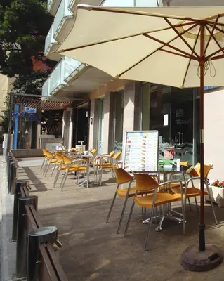 a row of tables and chairs with an umbrella at AQUA Hotel Nostre Mar Apartments in Pineda de Mar