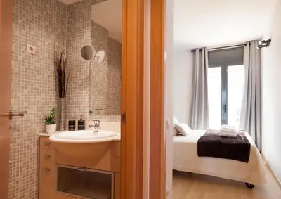 a bathroom with a sink and a bed and a window at Apartment Beach Front Canet in Canet de Mar
