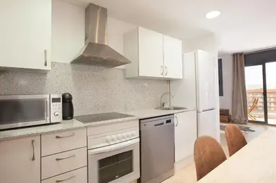 a kitchen with white appliances and a table with chairs at Apartment Beach Front Canet in Canet de Mar