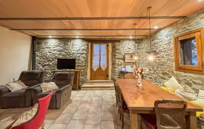 a living room with a table and a stone wall at Can Rovira de Fogars in Montseny