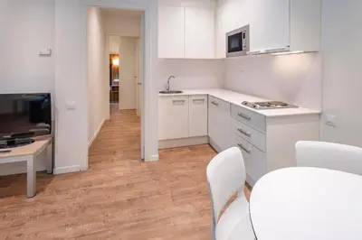 a kitchen with white cabinets and a table and chairs at Apartments Playa de Castelldefels in Castelldefels
