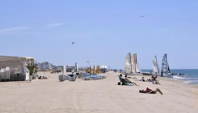 a group of people sitting on a beach with sailboats at Apartments Playa de Castelldefels in Castelldefels