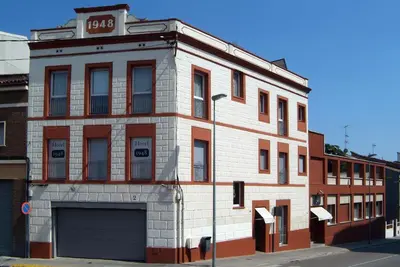 a white brick building with a garage on a street at Hotel 1948 Manresa in Manresa