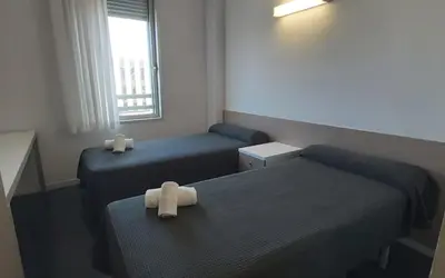 a small room with two beds and a window at Residencia Universitaria Resa Roberto de Nobili in Sant Cugat del Vallès
