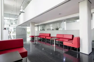a waiting room with red chairs and tables at Residencia Universitaria Resa Roberto de Nobili in Sant Cugat del Vallès