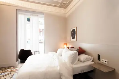 a white bedroom with a white bed and a window at DestinationBCN - Universitat Rooms in Barcelona
