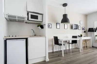 a kitchen with white cabinets and a table and chairs at Residencia Universitaria Resa Campus del Mar in Barcelona