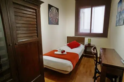 a small bedroom with a bed and a table and a window at Barcelona4Seasons - Central Palace in Barcelona