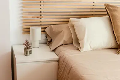 a bed with a wooden headboard next to a night stand at Capricho Apartamento Sitges in Sitges
