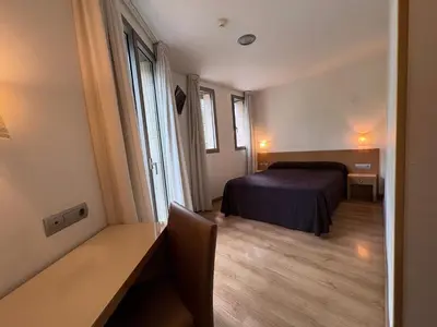 a bedroom with a bed and a desk and window at Hostal Rambla in Sant Boi del Llobregat