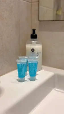 a bottle of detergent and two cups on a bathroom sink at Hostal Rambla in Sant Boi del Llobregat