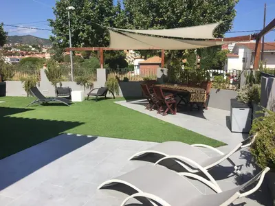 a patio with chairs and a table and grass at Villa Masnou Homelydays in El Carrer del Canonge