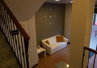 a living room with a white chair and a clock on the wall at Hostal Sant Pau in Barcelona
