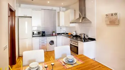 a kitchen with a wooden table and white appliances at Apartments Barcelona & Home Deco Viladomat in Barcelona