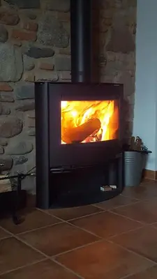 a fireplace with a fire in it in a room at Rincón de piedra BCN in Corró de Vall
