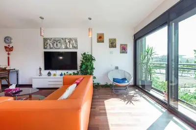 a living room with an orange couch and a large window at Jie Apartment in Sant Adria de Besos