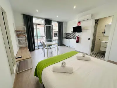 a bedroom with a large bed with a green blanket at Rainbow Apartments BY BLAUSITGES in Sitges