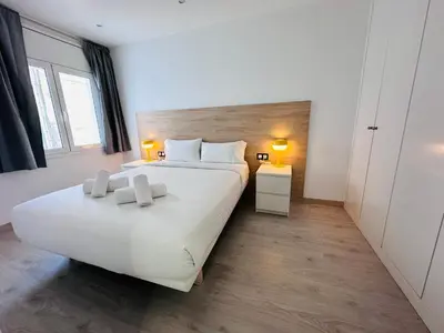 a bedroom with a large white bed and a window at Rainbow Apartments BY BLAUSITGES in Sitges