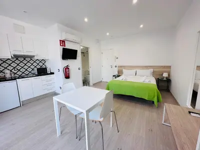 a bedroom with a green bed and a white table at Rainbow Apartments BY BLAUSITGES in Sitges