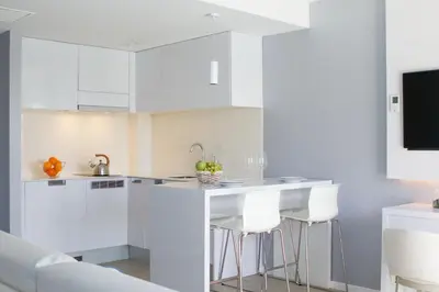 a kitchen with white cabinets and bar stools at Masd Mediterraneo Hotel Apartamentos Spa in Castelldefels