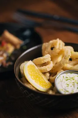 a bowl of onion rings with a lemon slice at Casa Gracia in Barcelona