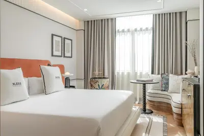 a white bedroom with a large bed and a chair at BLESS Hotel Barcelona in Barcelona