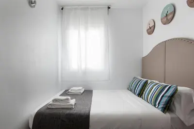 a white bedroom with a bed and a window at Tendency Apartments Fira in Hospitalet de Llobregat