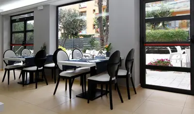 a dining room with tables and chairs and windows at Summer Hotel in Calella