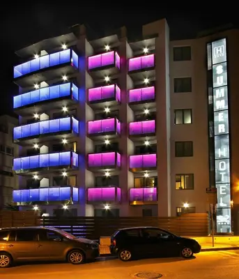 two cars parked in front of a building with purple lights at Summer Hotel in Calella