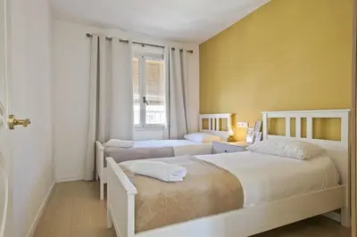 two beds in a bedroom with yellow walls at Apartment Leonor in Barcelona