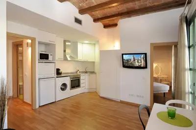 a kitchen with white appliances and a table in a room at Apart-Suites Hostemplo in Barcelona