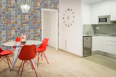 a kitchen with a table and chairs and a clock on the wall at Apart-Suites Hostemplo in Barcelona